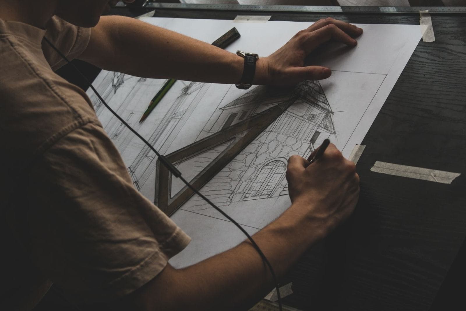 Hands drawing an architectural elevation or reviewing blueprints