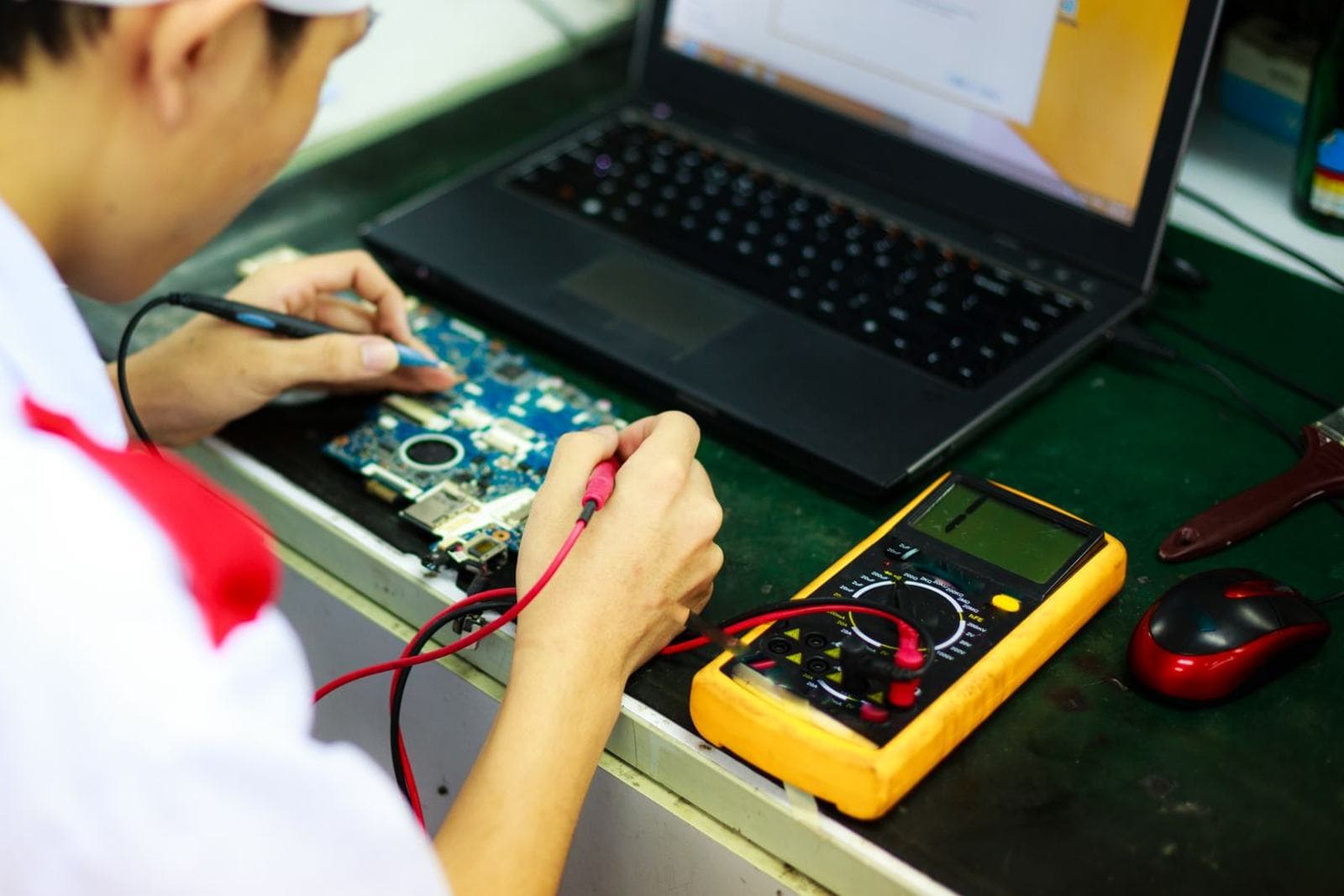Students building and testing electronics or machinery at a workbench