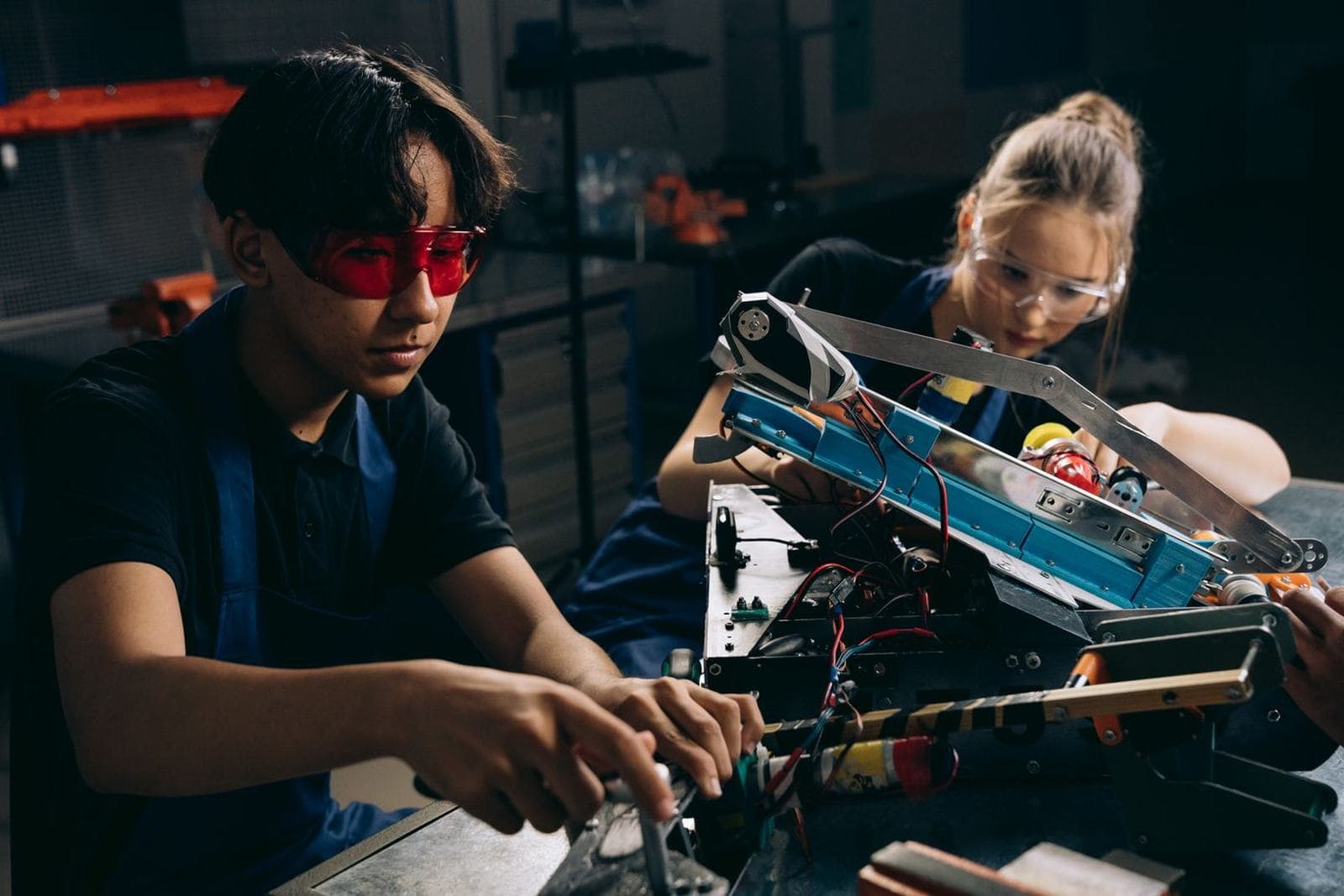Students building and testing electronics or machinery at a workbench
