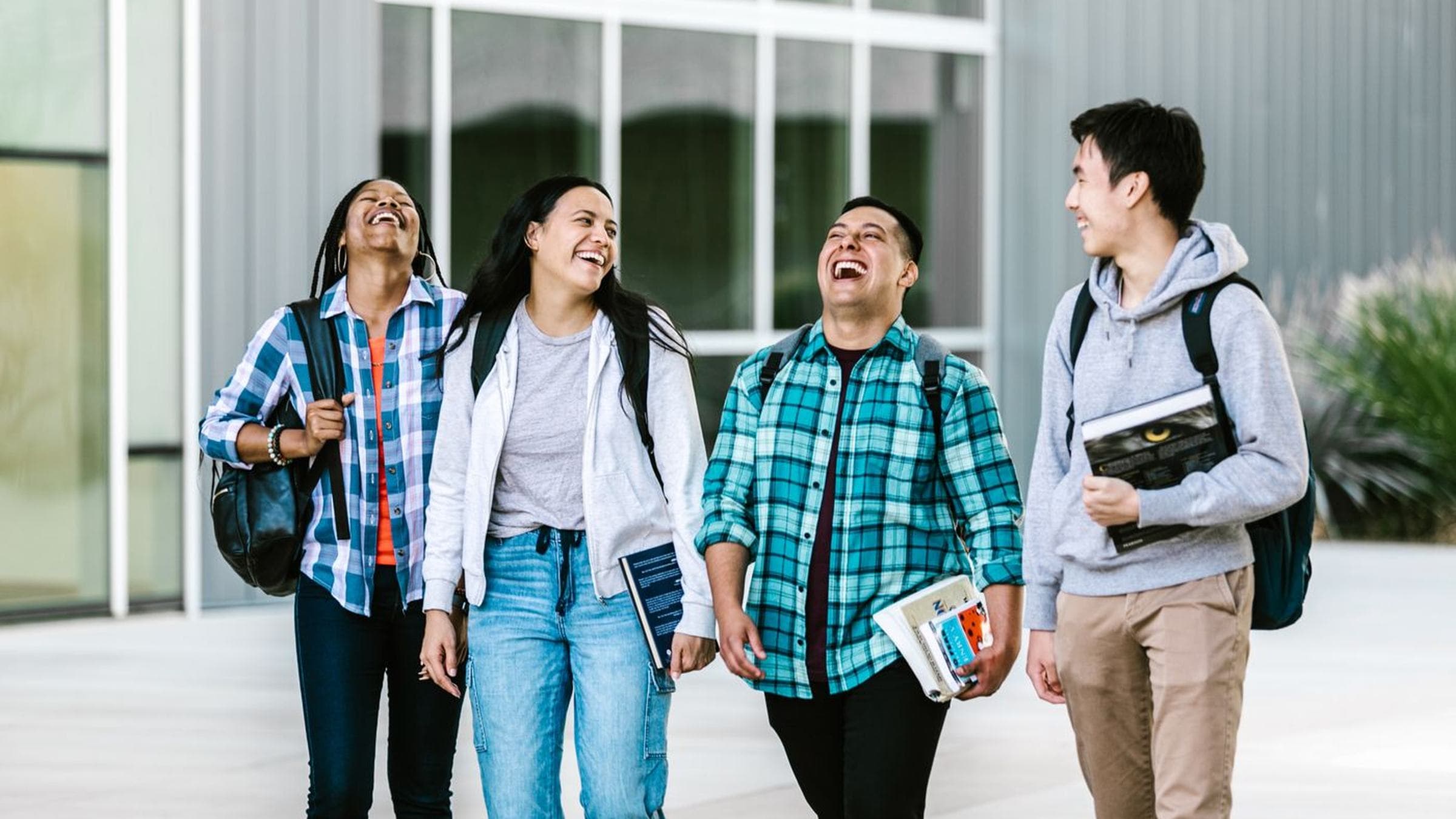 Four Iowa State students walking together outside a campus building, laughing
